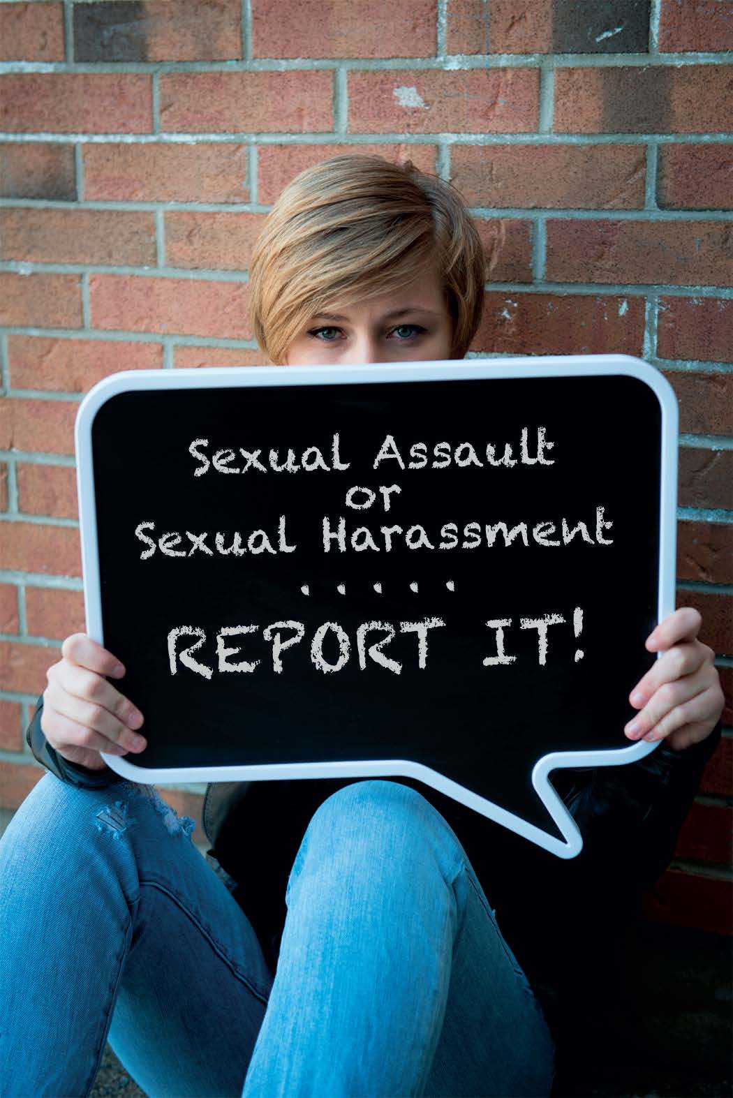 Female college student holding up sign that reads "Sexual Assault or Sexual Harassment.....Report it!"